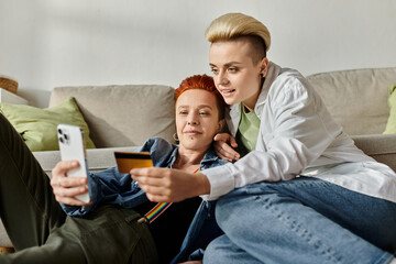 Two women, a lesbian couple with short hair, sit on the floor at home, discussing financial matters...