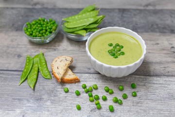 Cream soup with green pea on dark wooden background.  