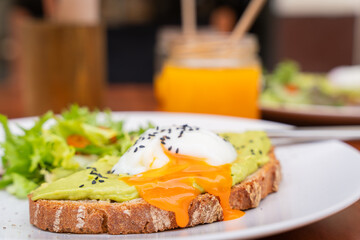 Delicious breakfast. Whole Wheat Toast with Avocado Cream topped with a Poached Egg. Toast with avocado cream and poached egg on top. selective focus. Soft focus.
