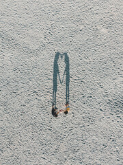 A lovely couple holding hands creates a heart-shaped shadow, captured from a top-down drone view.