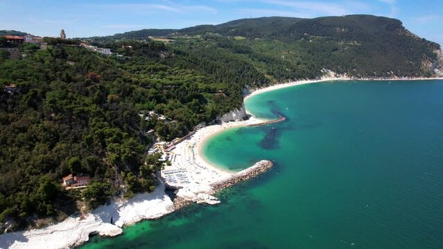 Aerial 4K view of Spiaggia del Frate beach and turquoise Adriatic sea. Scenic limestone cliffs of Monte Conero Riviera in Marche Italy