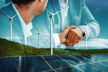 Double exposure graphic of business people handshake over wind turbine farm and green renewable...