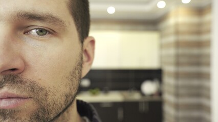 Close up of half of male face looking at camera, posing at kitchen. Slow motion