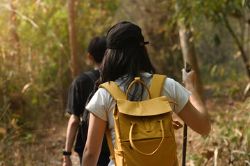Naklejka premium Rearview of Young transgender woman with backpack trekking with her boyfriend in the forest