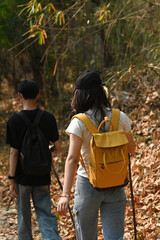 Rearview of Young transgender woman with backpack trekking with her boyfriend in the forest