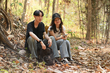 Portrait of Teenage LGBT Couple, Gay and Transgender woman sitting on the ground, resting during trekking in the woods