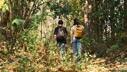 Rear view with Young LGBT couple with backpacks walking on a path through the woods