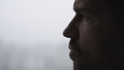 Young bearded man is thoughtful posing near the window. Slow motion - Powered by Adobe