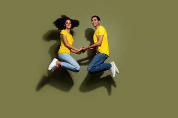 Full body portrait of two nice people jump empty space wear t-shirt isolated on khaki color...