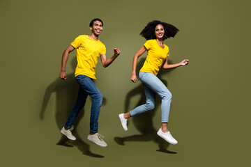 Full body portrait of two nice people run jump wear t-shirt isolated on khaki color background
