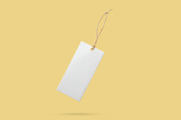 Blank price tag tied with string float on yellow background