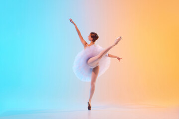 Rear view of young ballerina in white tutu doing arabesque in motion in neon light against blue-orange gradient background. Concept of art, movement, classical and modern fusion, beauty, fashion. Ad