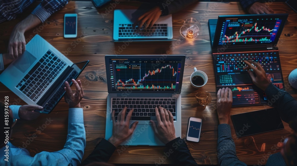 Aufkleber team collaboration around a table with laptops and stock market graphs, discussing investment opport