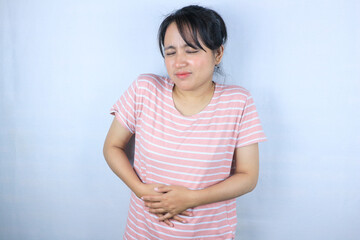 Fototapeta premium expression of young asian woman feeling menstrual pain while hand on stomach