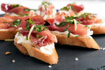 Deliziosi crostini freschi con prosciutto crudo, rucola e crema di formaggio, antipasti italiani 