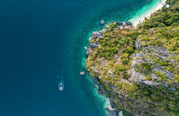 Aerial top view of a traditional philippine boat sails in sea with clear and turquoise water on the sunset. Palawan, Philippines