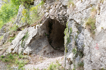 Stone wall with moss. Cave in the mountain.