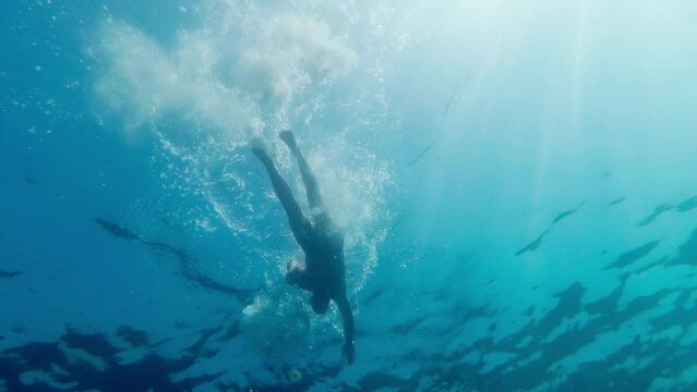 A man is swimming against a background of sky and sun. Shot from underwater.