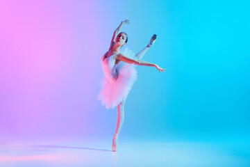 Portrait of young, flexible ballerina dancing, standing on tiptoe in action in neon light against vivid gradient background. Concept of art, movement, classical and modern fusion, beauty and fashion. © master1305