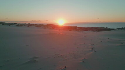 Drone sand dunes sunset view. Sunset descending casting golden glow at ocean