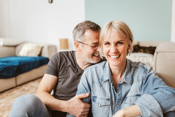 Joyful senior couple laughing and enjoying each other's company while relaxing at home on a cozy...