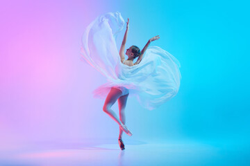 Portrait of young ballerina dancing standing on tiptoe with fabric in neon light against vivid gradient background. Concept of art, movement, classical and modern fusion, beauty and fashion. Ad