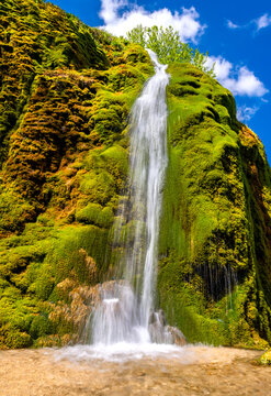 The &ldquo;Dreim&uuml;hlen Wasserfall&ldquo; formed from limestone deposits at the Ahbach creek in the Eifel, Germany. Long exposure of colorful tall cascade on a sunny May day. Tourist attraction and natural reserve.