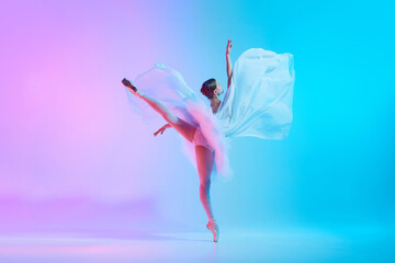 Graceful ballerina in tutu dancing standing on tiptoe with fabric flowing in motion in neon light against vivid gradient background. Concept of art, movement, classical and modern fusion, fashion. Ad © master1305