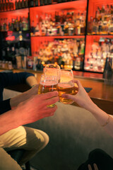Friends toasting with drinks at a lively bar in the evening