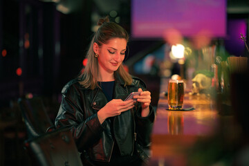 Young woman enjoying a night out at a cozy bar, checking her phone