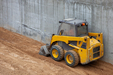 Mini excavator at work on building renovation site. 