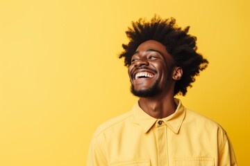 Portrait of a glad afro-american man in his 20s laughing isolated in soft yellow background