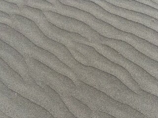 Gray volcanic sand dunes after windy weather and breeze in El Medano, Tenerife, Canary Islands,...