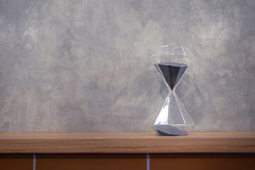A sandglass or hourglass is placed on table. Interior decoration object photo, selective focus.