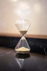 A sandglass or hourglass is placed on table. Interior decoration object photo, selective focus.