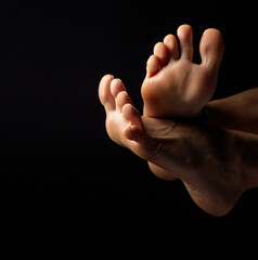 closeup, top of female feet with toes posing on black background