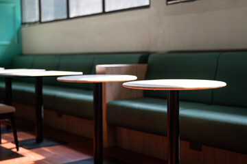 Round table set at the coffee bar with green sofa bench. Interior decoration and object photo,...