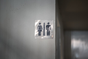 A toilet gender with men and women icon in gray scale banner which is attached on building wall....