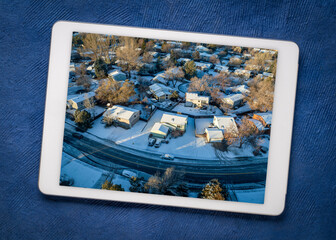 winter morning over a residential area of Fort Collins in northern Colorado with fresh snow, reviewing aerial image on a digital tablet