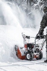 The self-propelled snow-plough blower. The man in warm clothes gloves instead of the big shovel has chosen a self-propelled engine snowplow outdoors