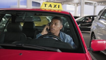 Angry taxi driver talking on the smartphone while sitting in the car