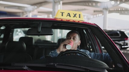 Happy male taxi driver enjoying coffee in the car.