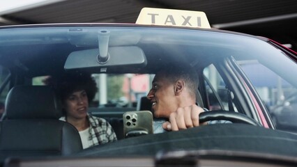Happy African American woman paying a taxi driver for a ride while sitting in the backseat in the...