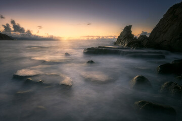 Sunset on Azkorri or Gorrondatxe beach, in Getxo, Bizkaia, with the waves passing over the rocks