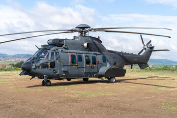 Black painted modern H225M military transport helicopter stationary on the ground