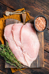 Fresh Raw chicken cutlet breast fillets on a wooden board, fowl meat. Wooden background. Top view
