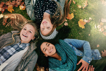 Above, teenagers or girls on park for autumn, relaxing and bonding together on grass with happiness. Nature, lawn and friends on summer holiday for chilling, hanging out and laugh outdoors with smile
