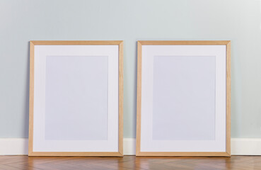 Blank picture frame templates on floor. Mint color wall and stylish parquet floor