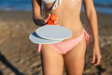 Woman holding a beach paddle and ball set