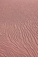 Abstract background, desert dunes and sand ripple textures on a dusky rose background, undulating contours in warm beiges and soft pinks